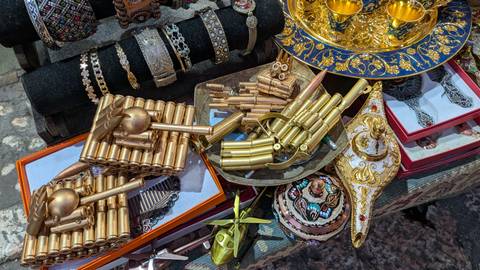 Colorful market table displaying souvenir items made from spent bullet casings alongside ornate cups.