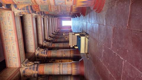 Interior hall of an ancient-Egypt set with ornate painted columns and a ceremonial throne at the far end.