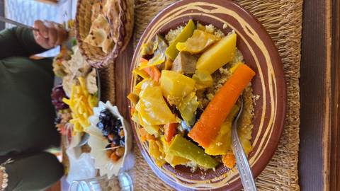 Close-up of a colourful Moroccan couscous dish with vegetables served on a traditional clay plate.