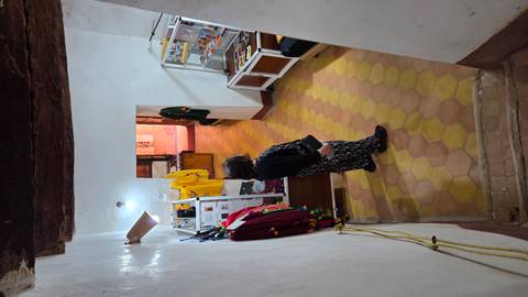 Woman browses items in a small shop corridor with hexagonal floor tiles and whitewashed walls.