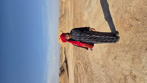 Solo traveller wearing red turban standing on flat arid plain beneath blue sky.