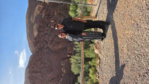 Couple posing in front of unique rounded rock formations with green valley below.