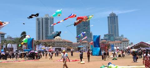 Colourful kite festival on an urban green with high-rise buildings in the background