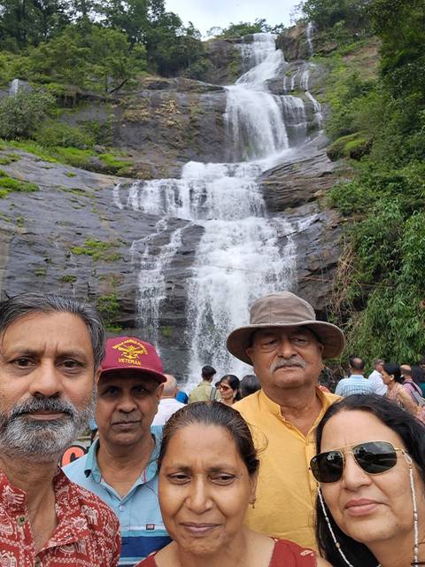 Crowded scene at the base of a cascading waterfall with tourists posing for photos