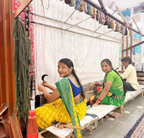 Women in colourful saris weaving intricate textiles on a traditional handloom