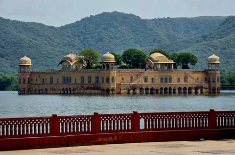 Jal Mahal palace sitting gracefully in the middle of a tranquil lake with green hills behind