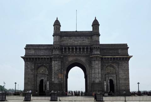 Monumental basalt Gateway of India arch standing against a pale sky in Mumbai