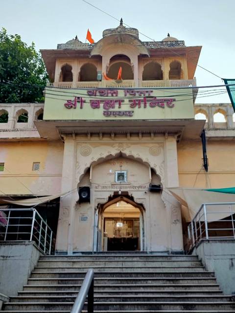 Arched entrance of the Brahma Temple featuring pastel yellow walls and Hindi signage