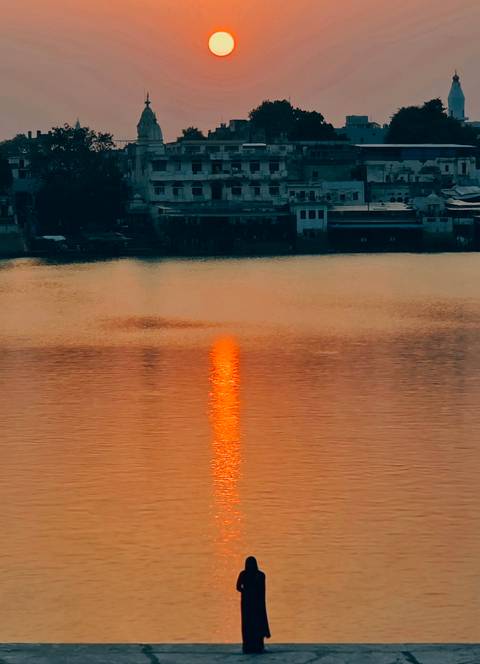 Golden column of sunset light reflecting across calm lake water