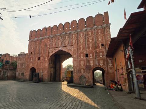 Early-morning sunlight hitting an ornate pink sandstone city gate in Jaipur