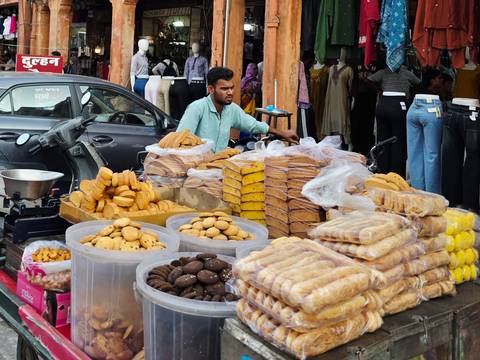 Street vendor selling stacks of assorted Indian biscuits and sweets from a cycle cart