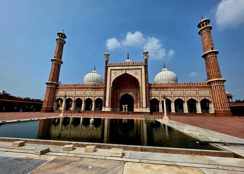 Grand Jama Masjid mosque with twin minarets and reflecting pool under a blue sky