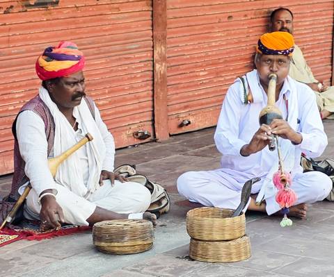 Snake charmer duo in turbans performing with a cobra basket on a street