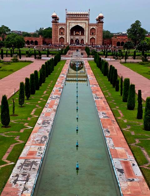 Long ornamental pool lined by manicured lawns and cypress trees in a Mughal garden.