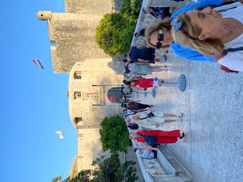 Crowds of tourists crossing the stone bridge into Dubrovnik’s fortified city gate on a sunny day.