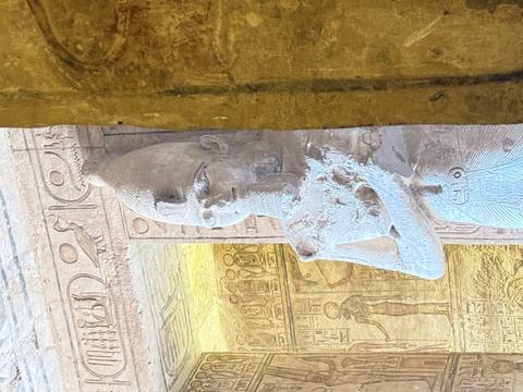 Relief-covered statue inside a richly decorated ancient Egyptian temple chamber.