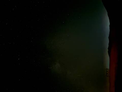 Star-filled night sky over a dark desert horizon with faint silhouettes of dunes.