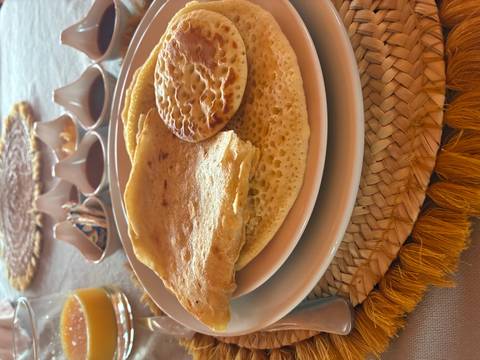 Moroccan breakfast plate with msemen and beghrir pancakes served on woven placemat.