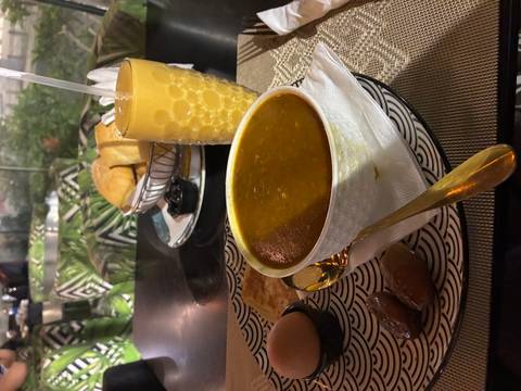 Bowl of harira soup with dates and juice on a patterned placemat in a cafe.