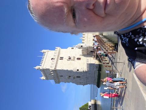 Partial selfie with Belém Tower and a queue of tourists crossing the wooden bridge to the historic fortress