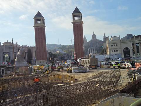 Urban construction site in front of Barcelona’s Venetian Towers with cranes and workers under morning light