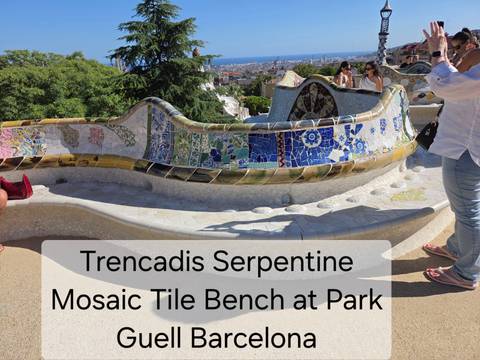 Colorful mosaic serpentine bench at Park Güell with large explanatory text overlay and tourists around
