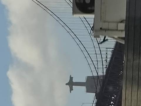 Distant silhouette of Cristo Rei statue beside a suspension bridge captured through haze