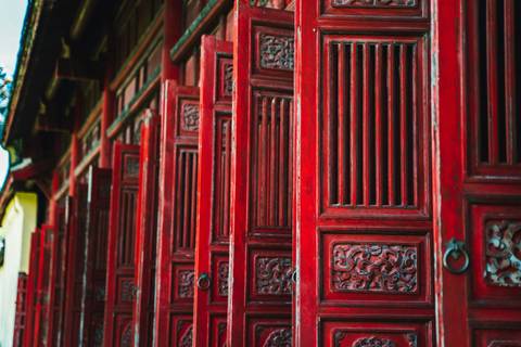 Detailed red lacquered wooden doors with ornate carvings in Vietnamese temple