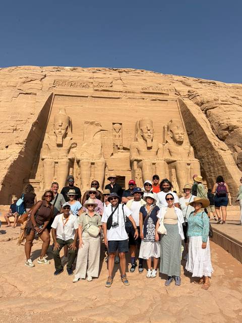 Tour group standing before the colossal seated statues of Abu Simbel temple