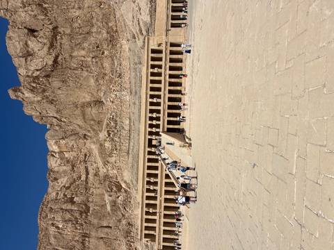 Expansive view of Hatshepsut temple carved into desert cliff under deep blue sky