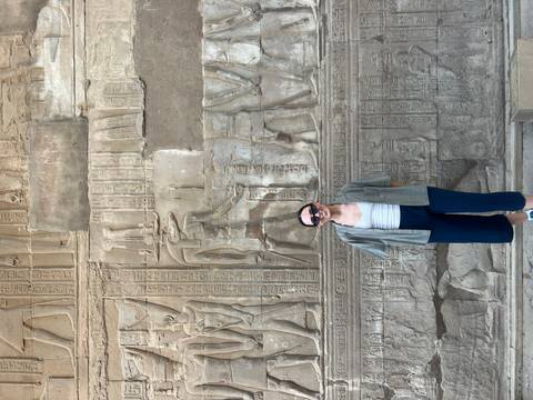 Smiling traveller poses before intricate hieroglyphic wall inside ancient temple