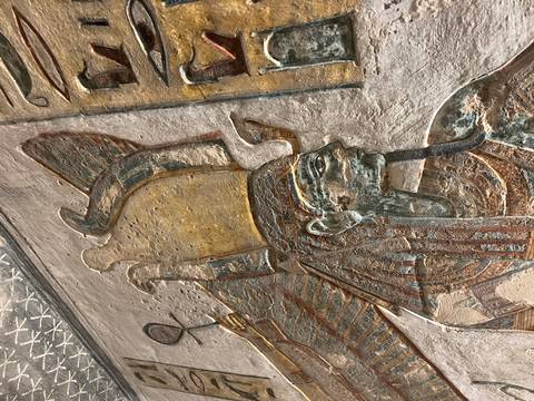 Close detail of carved Egyptian deity with colourful pigment remnants