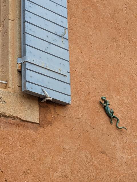 Rustic wall with blue wooden shutter and decorative bronze lizard