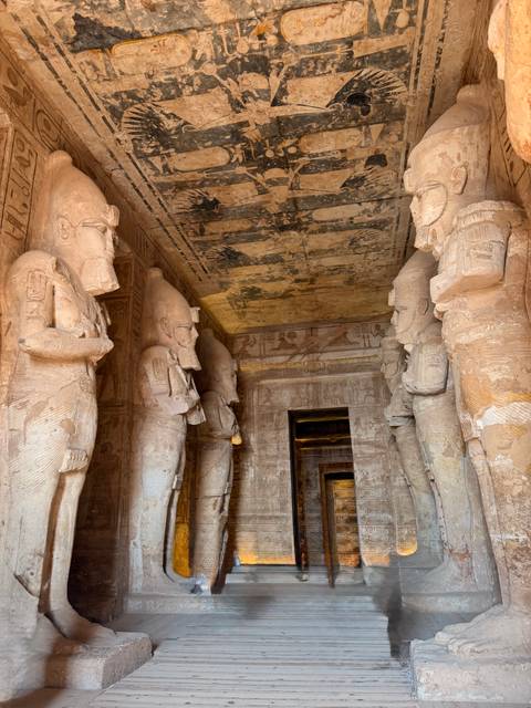 Interior corridor of Abu Simbel with towering carved statues lining both sides.