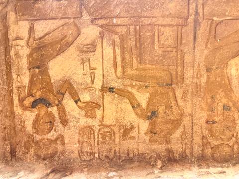 Close-up of ancient Egyptian wall painting showing figures offering items to a seated deity.