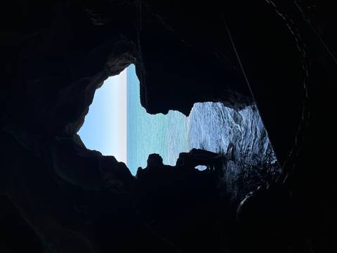 Ocean view framed by the dark, naturally sculpted opening of Hercules Cave.