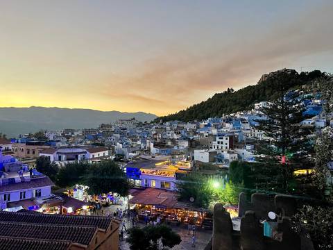 Twilight panorama of Chefchaouen’s blue-washed houses climbing a hillside beneath dusky sky.