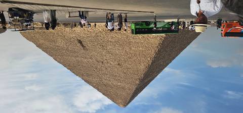 Great Pyramid of Giza towers over visitors and tour buses under partly cloudy sky.