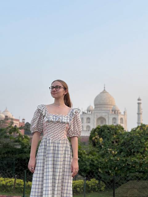 Young woman posing in front of the Taj Mahal on a clear day