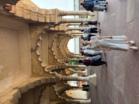 Visitors standing inside a sandstone arcade with scalloped Mughal arches