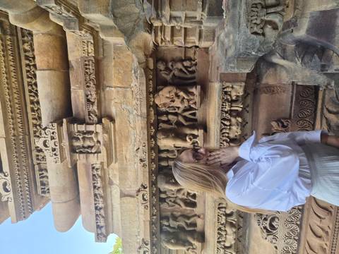 Woman observing detailed stone carvings on an ancient temple wall