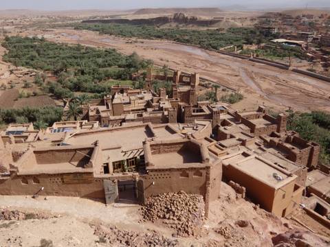 Aerial view over the earthen kasbah buildings of Ait Benhaddou beside a dry riverbed