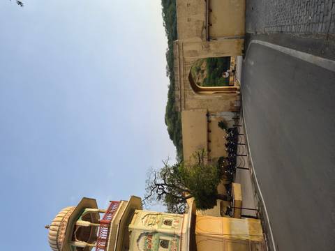 Quiet roadway leading through a yellow arched gate near forested hills