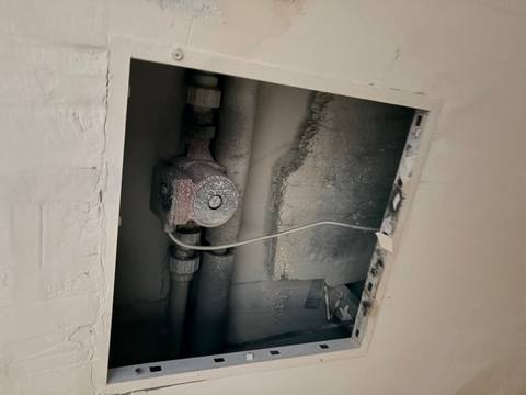 Dusty exposed plumbing fixture inside a wall cavity in a building