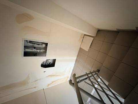 Stairwell area with open inspection panels and damaged walls in a building interior