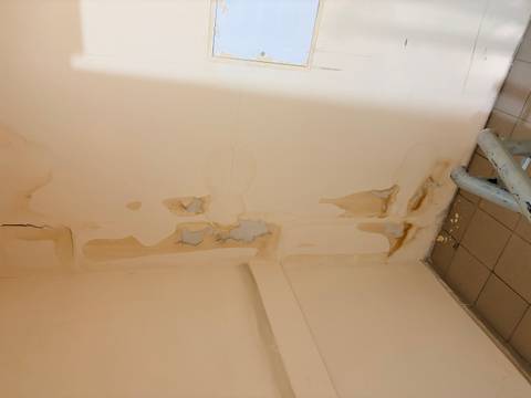 Peeling paint and cracks on an interior stairwell wall showing water damage