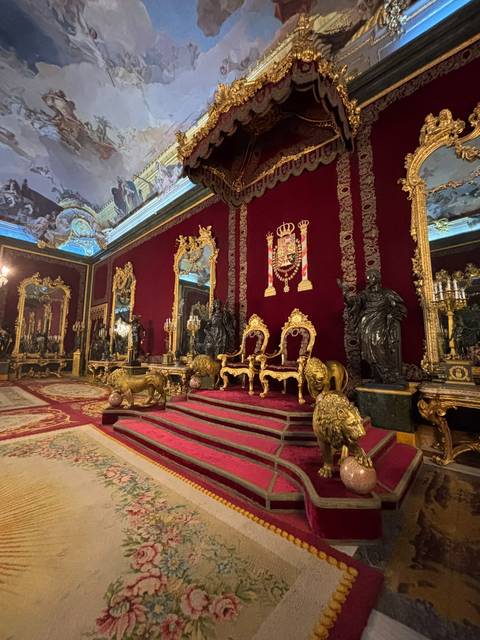 Rich red throne room with gilded lions and mirrors in the Royal Palace of Madrid.