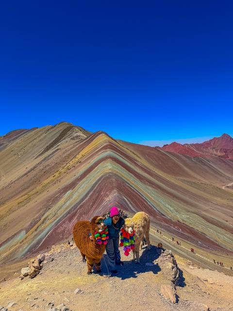 Vibrant striped slopes of Rainbow Mountain stretching beneath a clear cobalt sky.