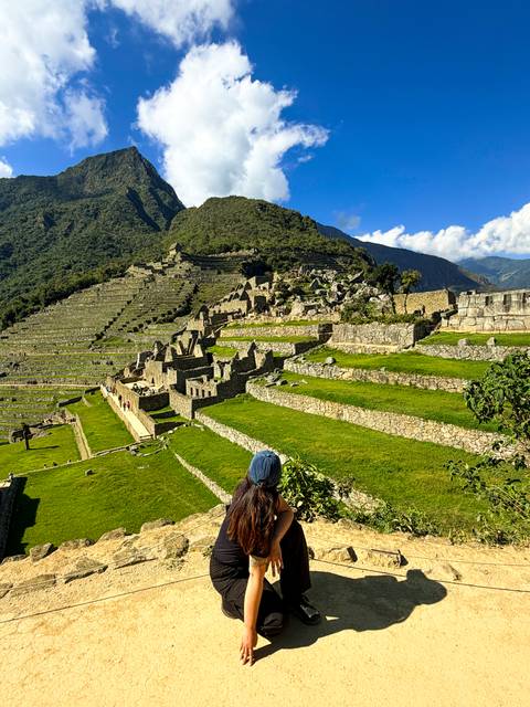 Lush green terraces and ruined stone walls of Machu Picchu viewed from above.
