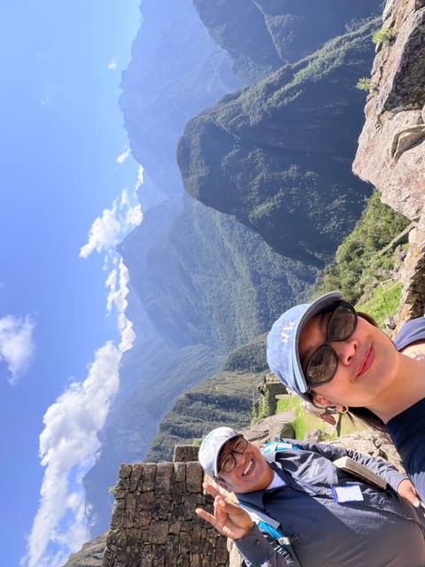 Vertical selfie overlooking deep green Andean valleys and jagged peaks.
